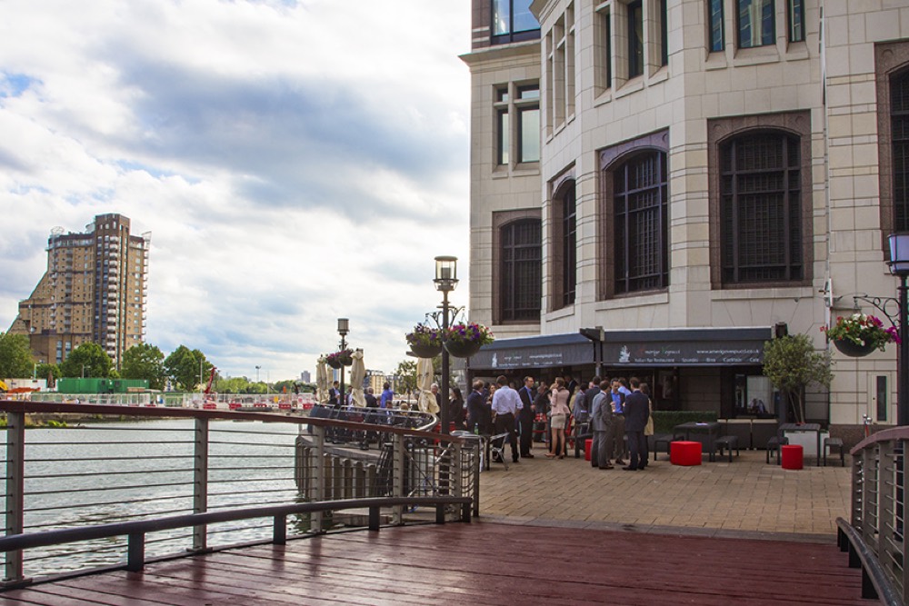 The waterside terrace of Amerigo Vespucci beside the dock at Canary Wharf, with guests under the awning