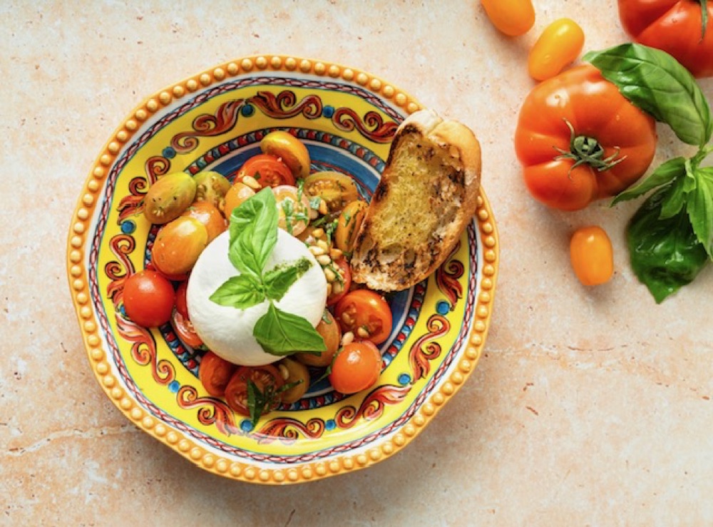 Burrata with heritage tomatoes and grilled ciabatta on a hand-painted Sicilian plate