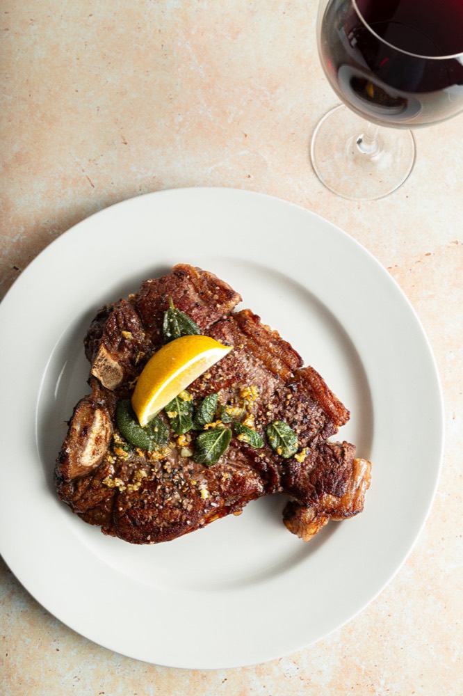 Chargrilled T-bone steak with lemon and herbs, red wine alongside