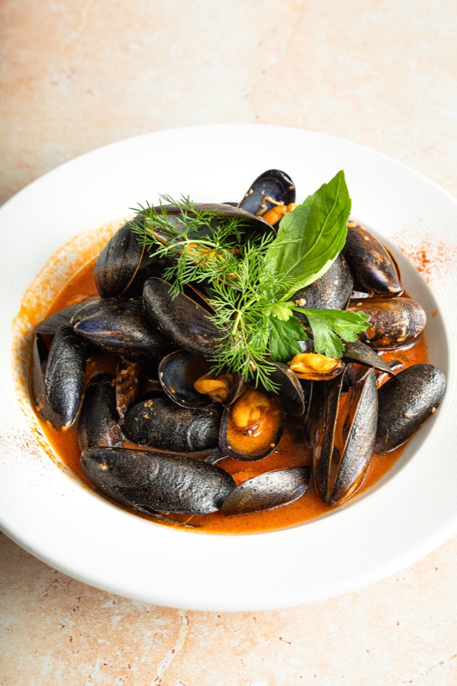 Mussels in a rich tomato broth topped with fresh herbs